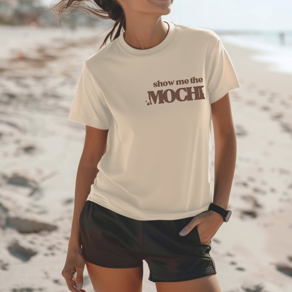 Natural color t-shirt with Show Me the Mochi text, Hawaii foodie shirt worn at the beach